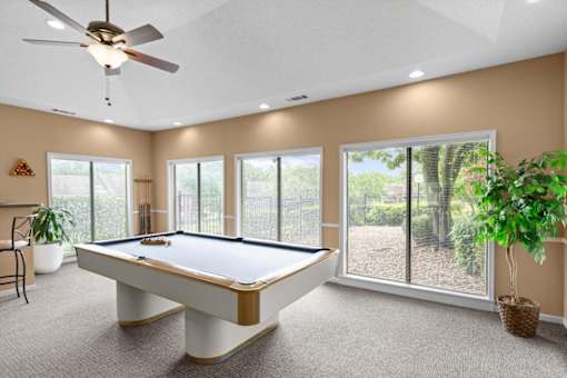 A pool table in a room with a ceiling fan and sliding glass doors.