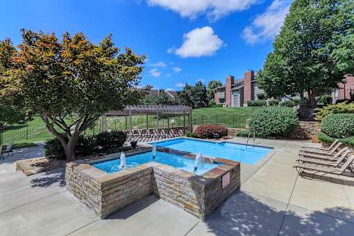 A pool with a waterfall and a fence in the background.