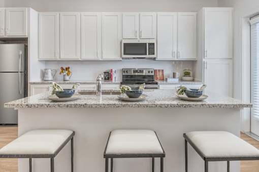 A kitchen with white cabinets and a granite countertop.