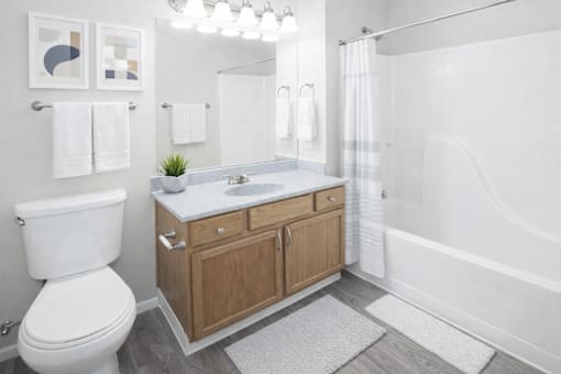 A bathroom with a white toilet, a wooden cabinet, and a glass shower door.