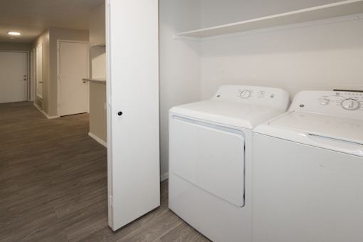 A white bed with a white mattress and pillow is in a room with a white wall and a white door.