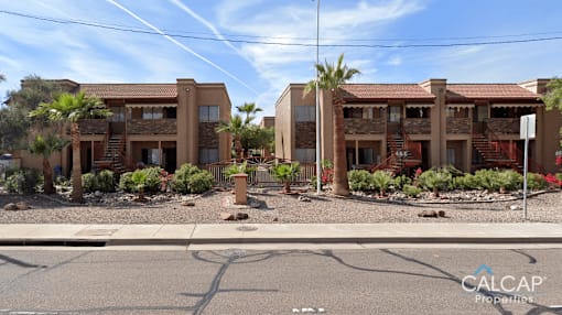 A sunny day at a residential area with two buildings and palm trees.