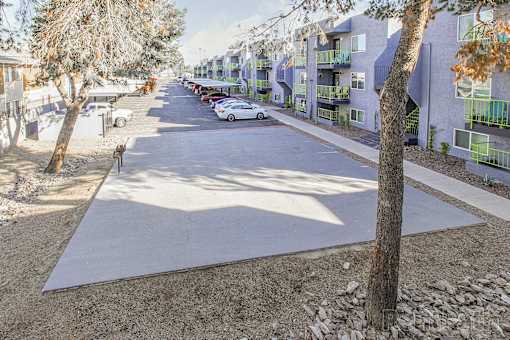 A tree-lined street with apartment buildings on the right.
