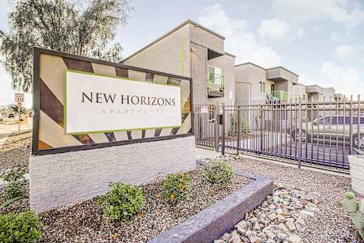 A sign for New Horizons Apartments is displayed in front of a building.