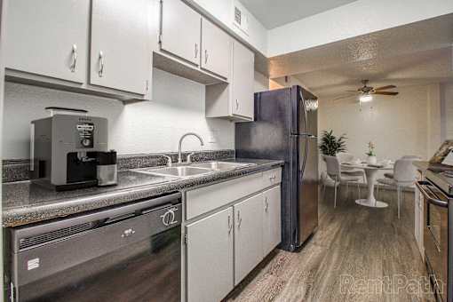 A kitchen with a refrigerator, sink, and stove.