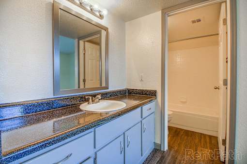 A bathroom with a sink, mirror, and cabinets.