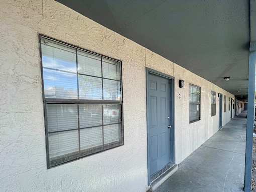 A long hallway with a blue door and windows.