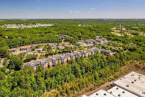 A bird's eye view of a residential area with apartment buildings surrounded by trees.