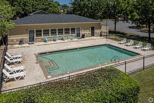A pool with a black fence and white chairs.