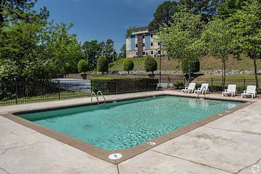 A small pool surrounded by a black fence and trees.