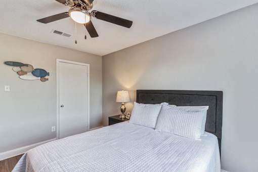 A bedroom with a bed, nightstand, and a ceiling fan.