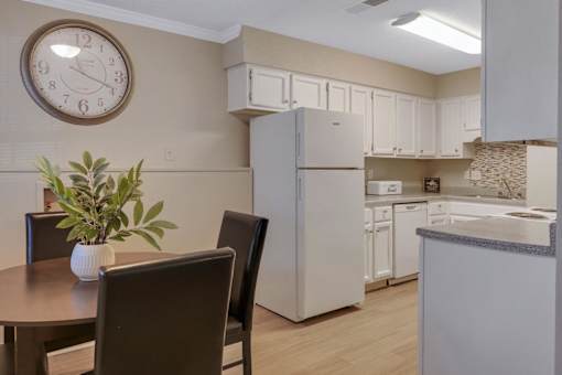 A kitchen with a table and chairs and a clock on the wall.