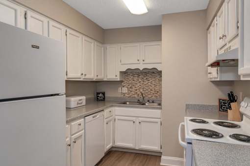 A kitchen with white appliances and cabinets.