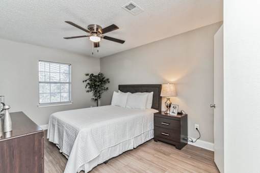A bedroom with a bed, nightstand, and a ceiling fan.