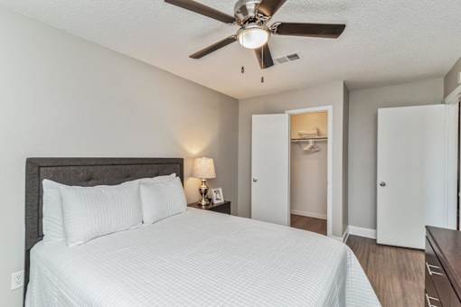 A bedroom with a large bed and a ceiling fan.