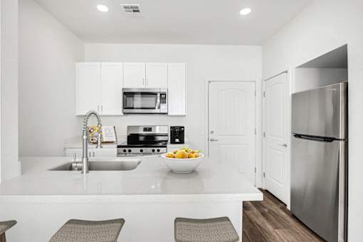 A modern kitchen with a bowl of fruit on the counter.