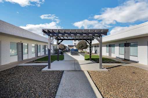 A modern building with a gravel pathway leading to a covered walkway.