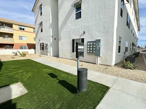 A white building with a grey trash can in front of it.