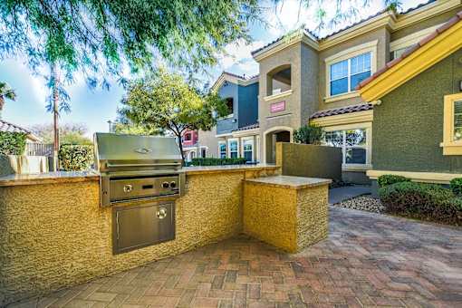 A backyard with a grill and a wall.