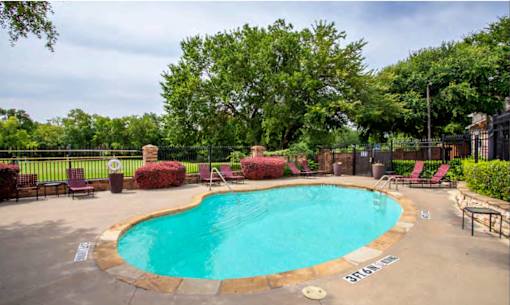 A small pool surrounded by trees and chairs.