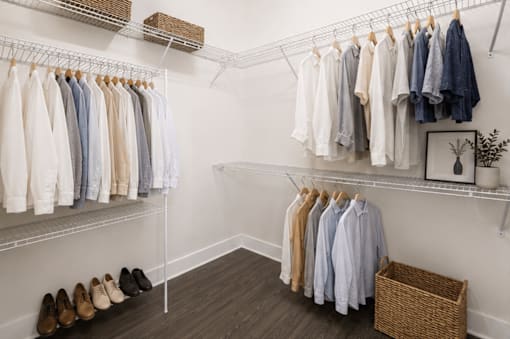 A white closet with clothes and shoes.