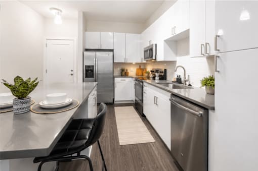 A modern kitchen with a black chair and a plant on the counter.