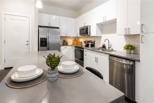 A modern kitchen with a dining table set for two.