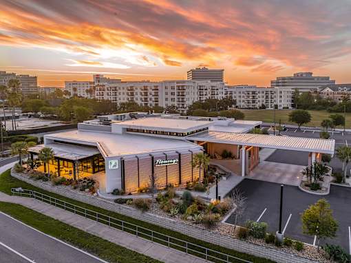 A modern building with a glass facade is illuminated by the setting sun.