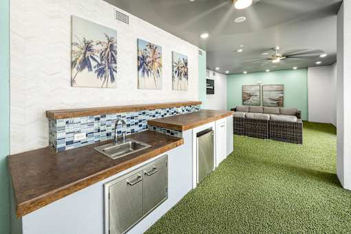 A kitchen with a sink, dishwasher and a green carpet.
