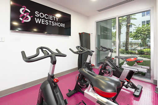 A gym with exercise equipment and a sign that says Society Westshore.