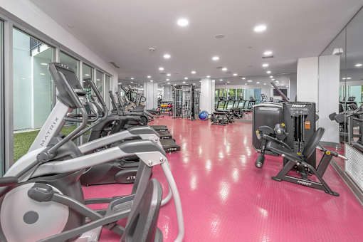 A gym with a red floor and various exercise equipment.