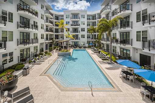 A large swimming pool surrounded by balconies and lounge chairs.