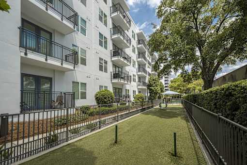 A white apartment building with a black fence and green grass in front.