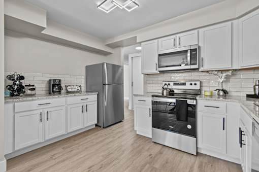 A modern kitchen with white cabinets and stainless steel appliances.