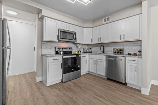 A kitchen with white cabinets and stainless steel appliances.