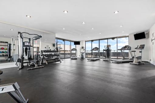 a spacious fitness room with cardio equipment and floor to ceiling windows