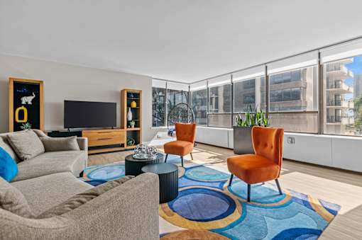 A living room with a grey couch, a black coffee table, a television, and a blue rug.