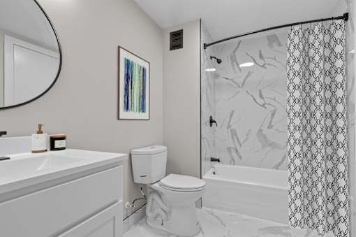A bathroom with a white toilet, sink, and shower.