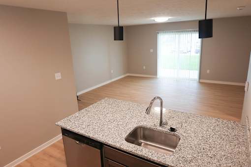 A kitchen with a granite countertop and a stainless steel sink.