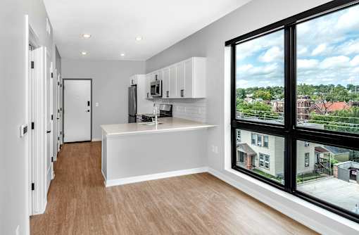 an empty living room with a large window and a kitchen