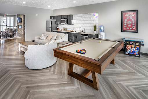 A pool table is in the middle of a room with a white couch and a wooden coffee table.