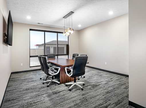 A conference room with a large table and chairs.