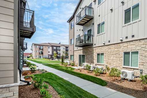 A row of apartment buildings with balconies and landscaping.
