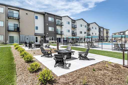 A sunny day at a residential complex with a pool and a patio area.