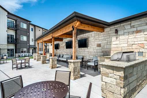 A patio with a table and chairs is surrounded by stone walls.