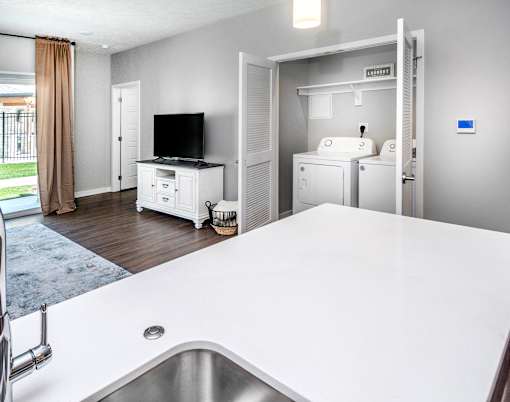 A modern kitchen with a white countertop and a stainless steel sink.