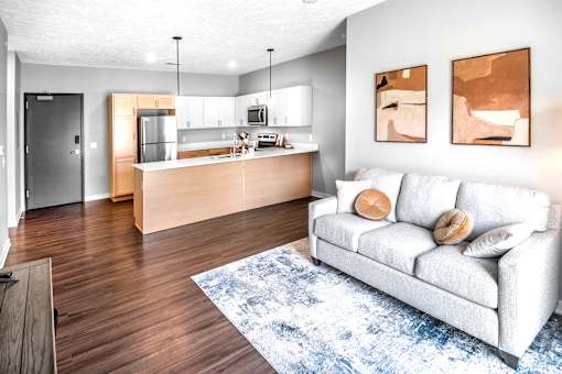 A modern living room with a white couch and a kitchen area in the background.