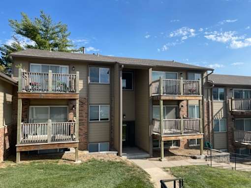 Exterior apartment building at Fox Run Apartments featuring balconies, entrances, and landscaped grounds.