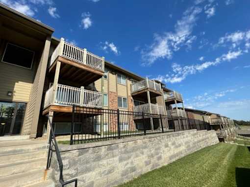 Fox Run Apartments buildings with private balconies, landscaped grounds, and a stone entrance feature.