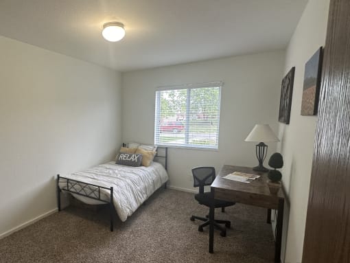 A cozy bedroom in the Park 25 Apartments model unit with a comfortable bed and natural light.